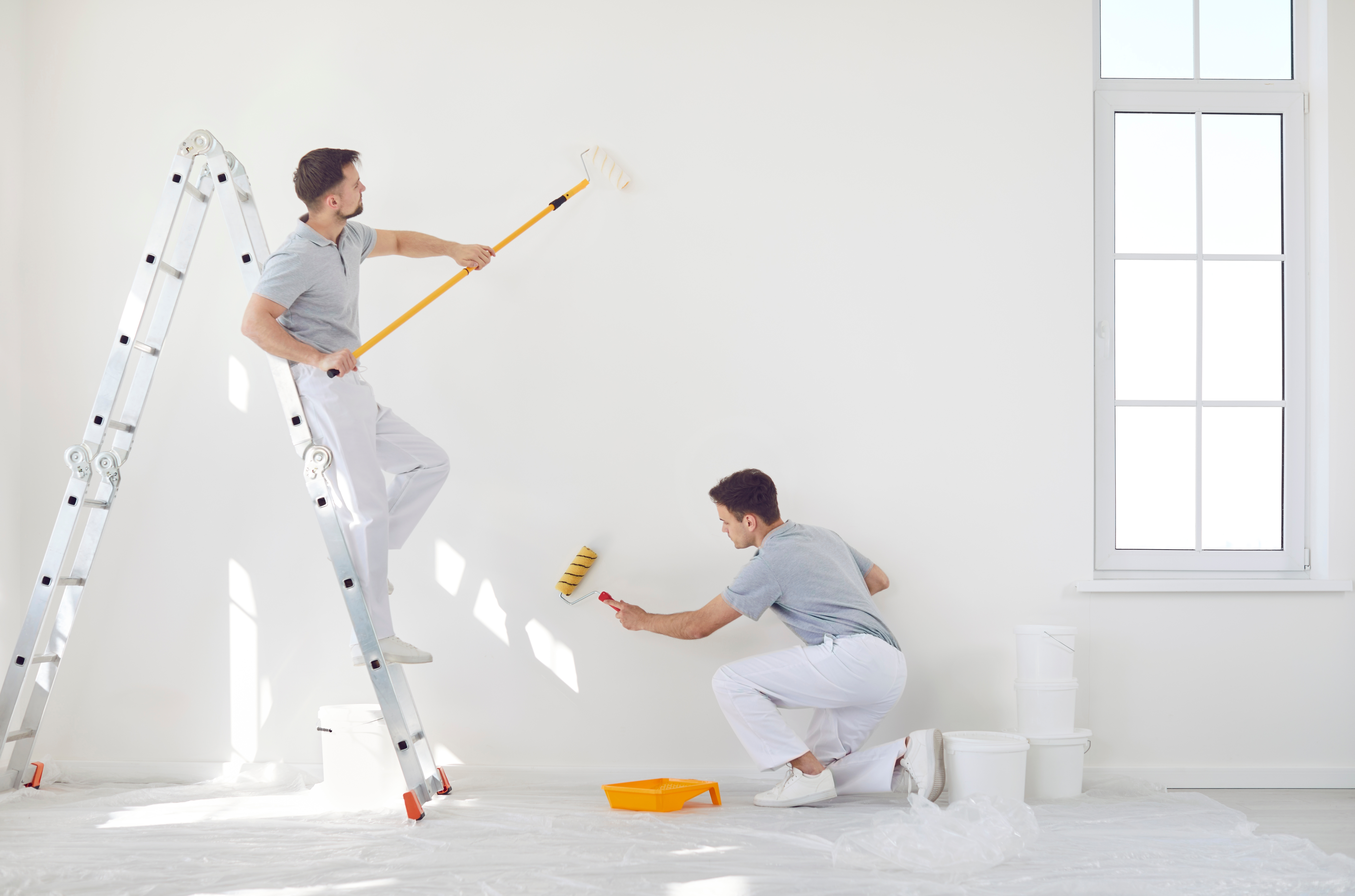 Showing two men decorating the interior of a house. 